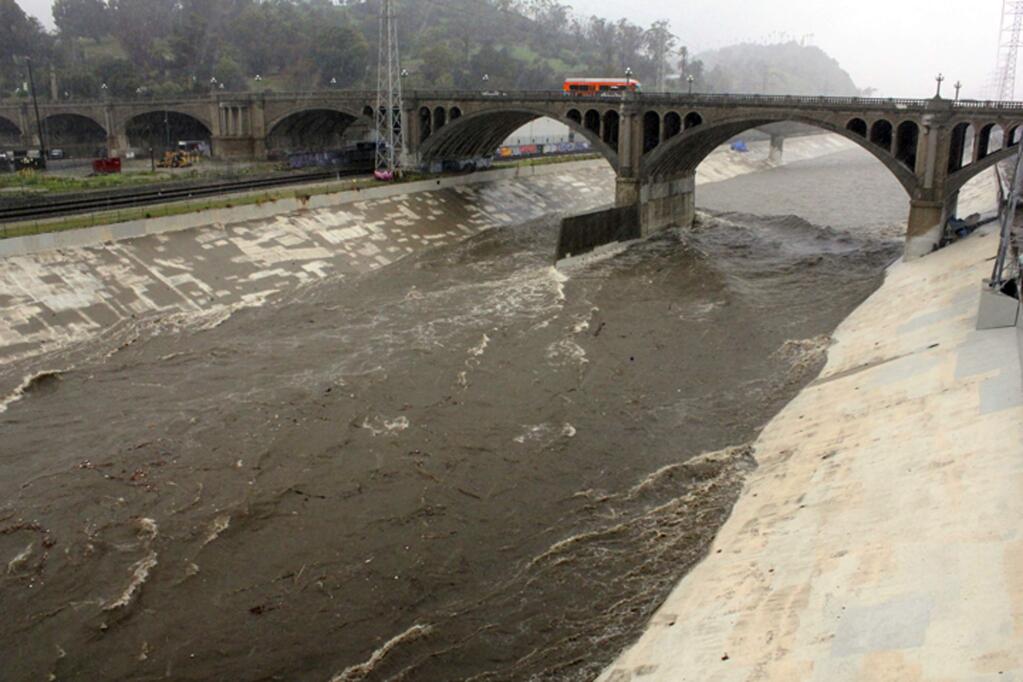 FILE - In this Feb. 2, 2019 file photo, water races down the concrete-lined channel of the swollen Los Angeles River, under the North Broadway Bridge near downtown Los Angeles, as a powerful storm drenches California. California is drenched and its mountains are piled high with snow after winter storms that were unimaginable just a few months ago. (AP Photo/John Antczak, File)