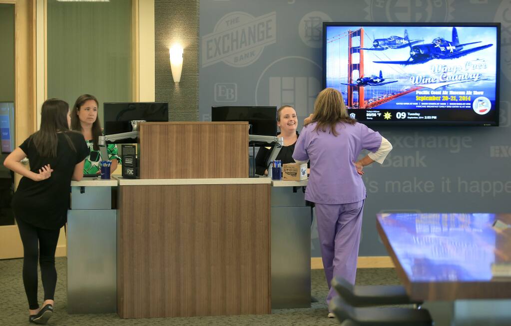 PHOTO: 1 BY KENT PORTER/ THE PRESS DEMOCRAT-Exchange Bank employees Meegan Kamanaka, in green at left, and Caitlin Bradbury help customers at the remodeled Windsor branch.