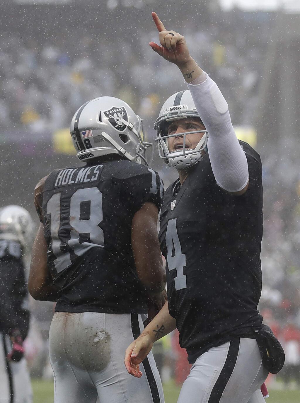 Oakland Raiders quarterback Derek Carr (4) and wide receiver Andre Holmes (18) celebrate after connecting on a touchdown pass during the first half of an NFL football game against the Kansas City Chiefs in Oakland, Calif., Sunday, Oct. 16, 2016. (AP Photo/Marcio Jose Sanchez)