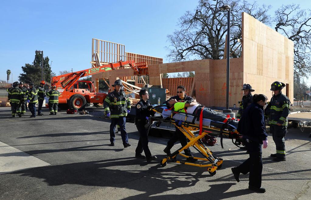 Emergency medical personnel help a worker that was injured when a building under construction collapsed, along Cleveland Avenue near Coddingtown Mall, in Santa Rosa on Thursday, December 14, 2017. (Christopher Chung/ The Press Democrat)