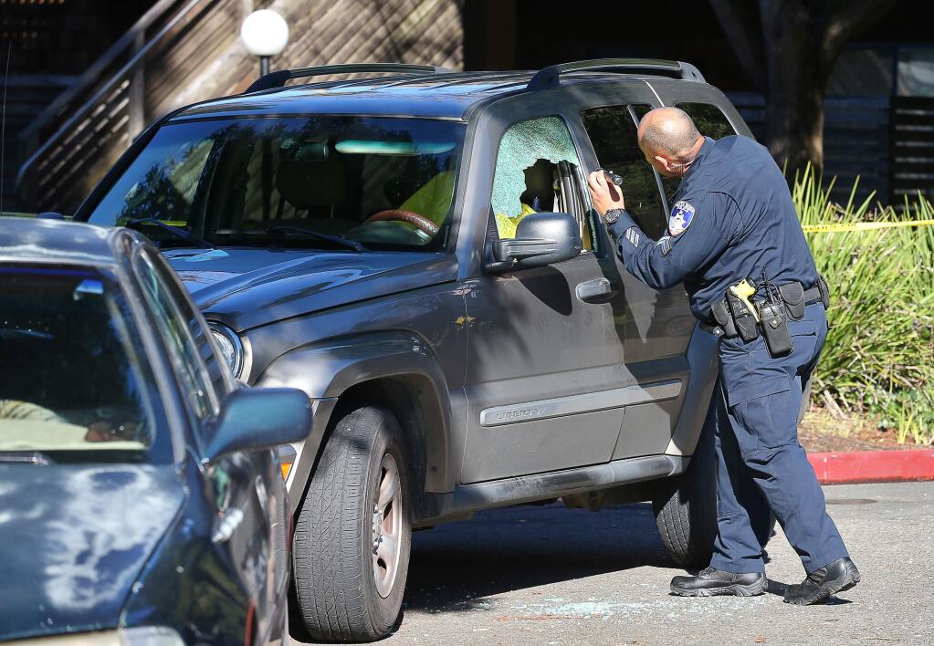 Santa Rosa Police Officer Matt Sanchez looks into a vehicle involved in a shooting, at the end of Herbert Street in Santa Rosa on Monday, March 11, 2019. (Christopher Chung/ The Press Democrat)