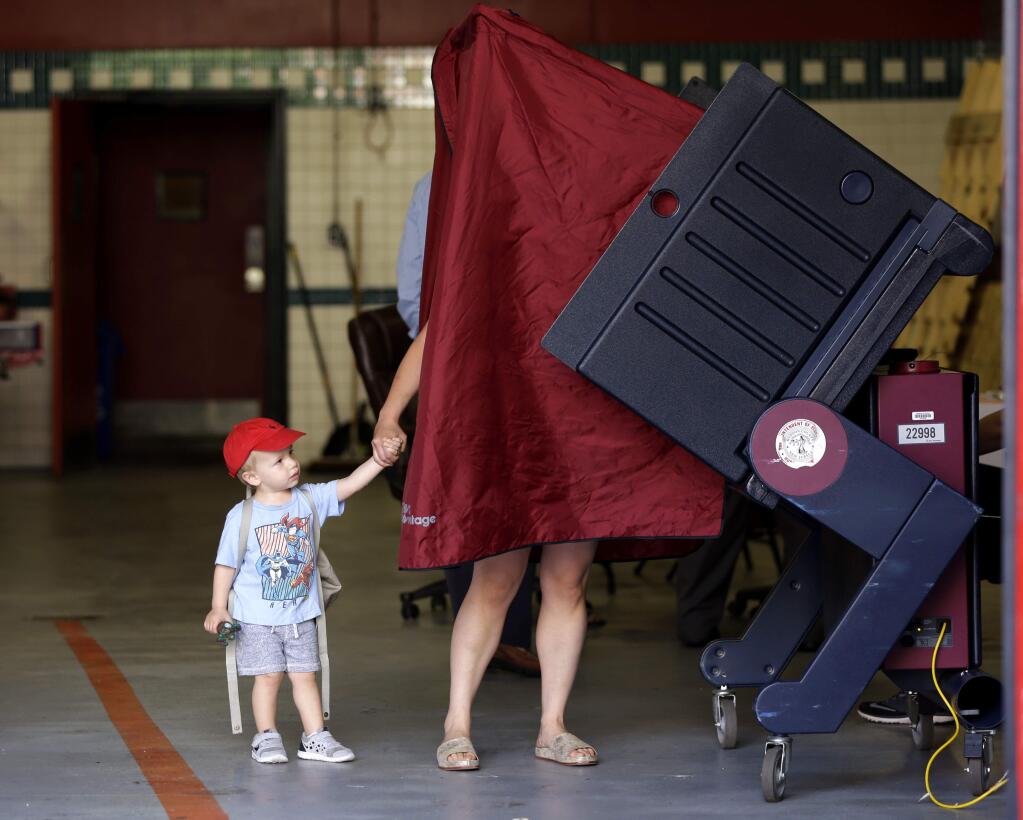 James Percella, 2, holds his mothers hand as she steps into a voting booth in Hoboken, N.J., in June. Some 33 percent of married men earlier this month said Hillary Clinton would get their wives' votes, but 45 percent of married women say they will vote for Clinton.