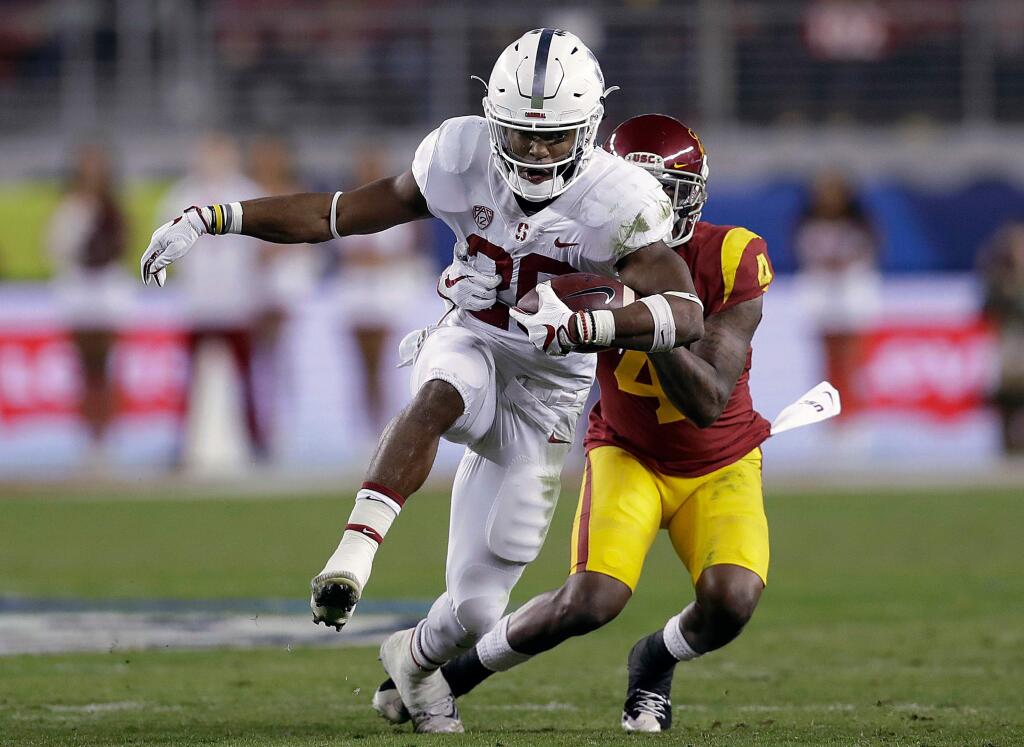 In this Dec. 1, 2017, file photo, Stanford running back Bryce Love runs in front of USC safety Chris Hawkins during the first half of the Pac-12 Conference championship game in Santa Clara. After rushing for more than 2,000 yards and finishing as the Heisman Trophy runner-up as a junior, Love easily could have decided to enter the NFL draft. (AP Photo/Marcio Jose Sanchez, File)