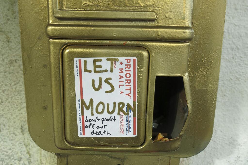 In this photo taken Wednesday, Dec. 7, 2016, a message posted on a gold-painted phone booth reads, 'Let Us Mourn' outside an Oakland artist collective known as The Salt Lick in Oakland, Calif. Oakland and its abandoned warehouses have long been hospitable to an underground art scene that helped put this gritty city on the world art map. But now the art and music underground is panicking, and bracing for a crackdown. They're fearful because of safety issues exposed by the fire that killed 36 people at a warehouse dance party. (AP Photo/Jocelyn Gecker)