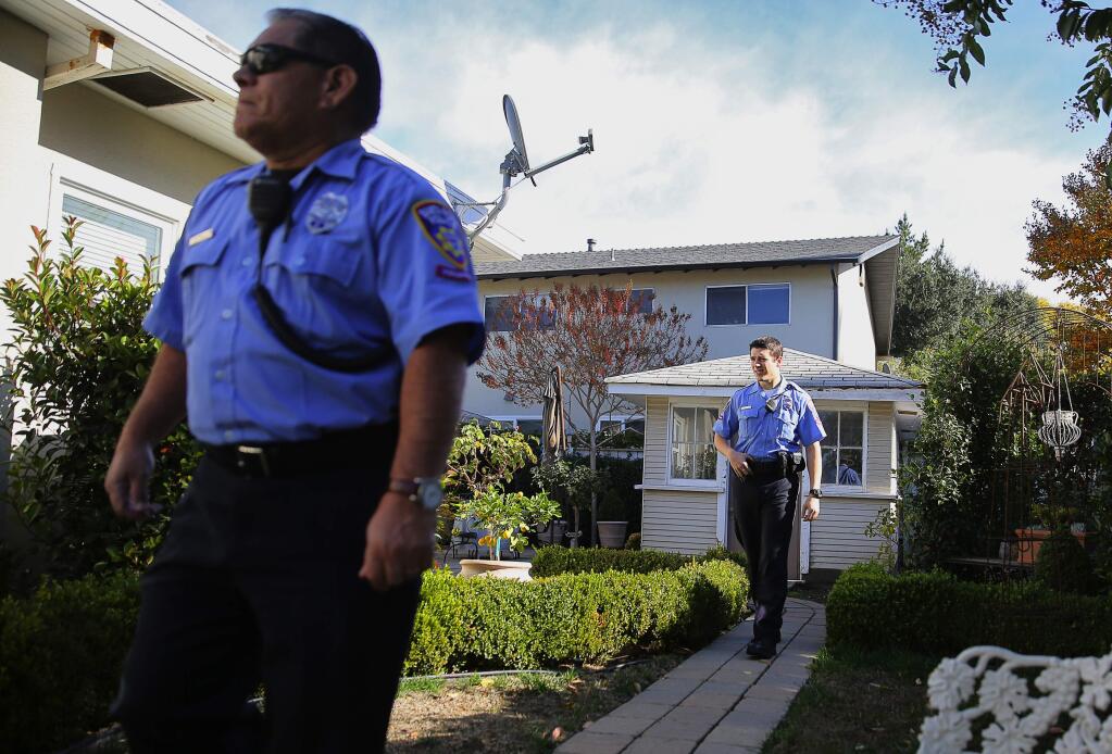 Santa Rosa Police Department volunteers Dave Tacla, left, and Christopher Billings walk the perimeter of a home during a vacation check, in Santa Rosa, on Wednesday, November 25, 2015. The police department recently started offering residents the option of signing up to have police volunteers check their homes while they are on vacation.(Christopher Chung/ The Press Democrat)