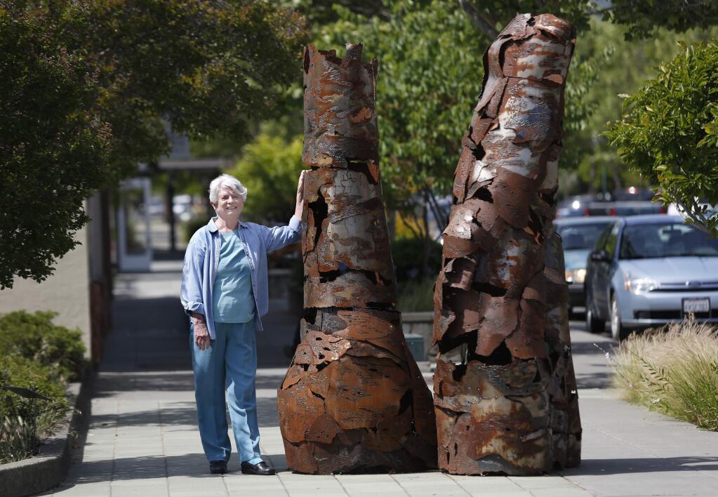 PHOTO: 1 by BETH SCHLANKER / The Press Democrat -Joyce Mann, 80, stands next to “Column I, Column II” by Beth Hartmann along the Sculpture Trail in Cloverdale. Below, “Wing Obelisk,” left, by Peter Crompton and “Metaface” by Pierre Riche.