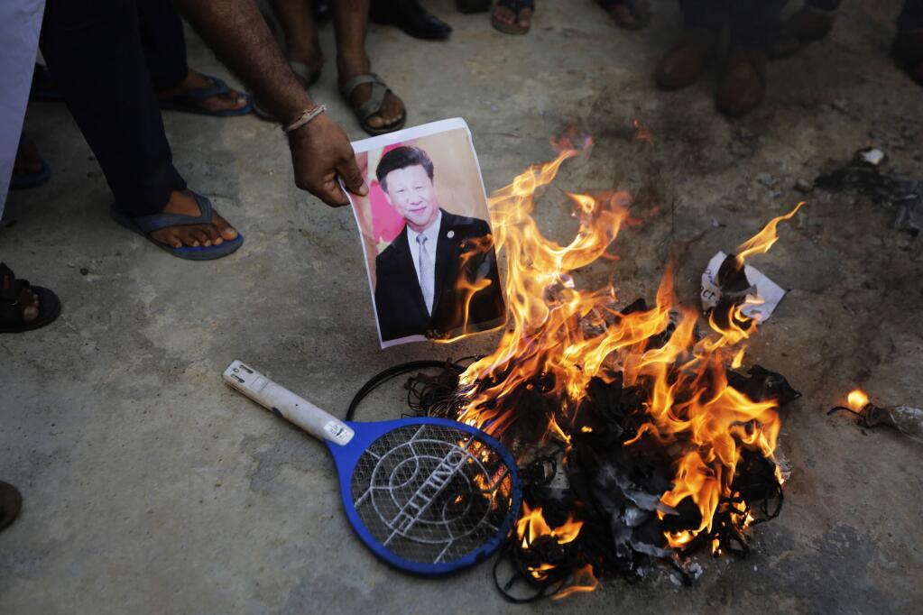 An Indian man burns a photograph of Chinese president Xi Jinping during a protest against China in Ahmedabad, India, Tuesday, June 16, 2020. At least three Indian soldiers, including a senior army officer, were killed in a confrontation with Chinese troops along their disputed border high in the Himalayas where thousands of soldiers on both sides have been facing off for over a month, the Indian army said Tuesday. (AP Photo/Ajit Solanki)