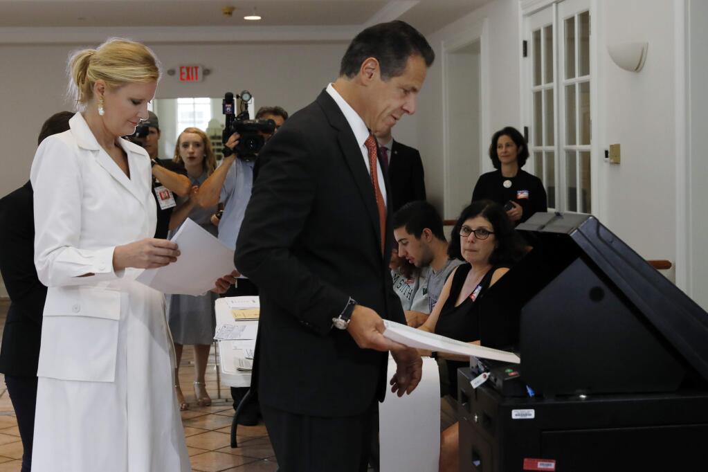 New York Gov. Andrew Cuomo, accompanied by his girlfriend Sandra Lee, puts his primary election ballot in a scanner at the Presbyterian Church of Mount Kisco, in Mt. Kisco, NY, Thursday, Sept. 13, 2018. (AP Photo/Richard Drew)