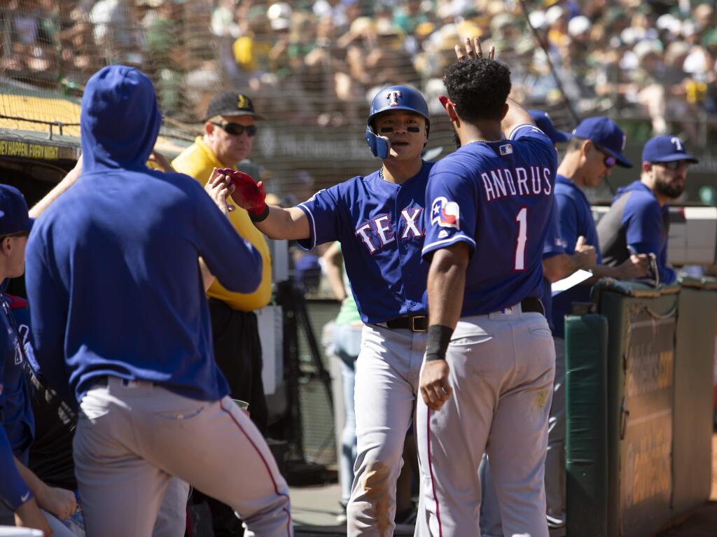 Texas Rangers' Shin-Soo Choo, center, is greeted by his teammates after scoring on a single by Danny Santana during the fourth inning of a baseball game against the Oakland Athletics, Sunday, Sept. 22, 2019, in Oakland, Calif. (AP Photo/D. Ross Cameron)