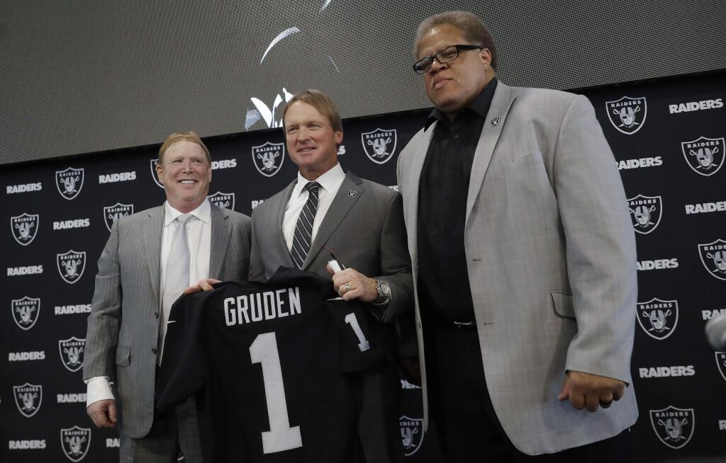 FILE - In this Jan. 9, 2018, file photo, Oakland Raiders new head coach Jon Gruden, center, poses for photographs next to owner Mark Davis, left, and general manager Reggie McKenzie during an NFL football press conference in Alameda, Calif. The Raiders have fired general manager Reggie McKenzie less than two years after he was named the NFL's executive of the year. A person familiar with the move says McKenzie was let go on Monday, Dec. 10, 2018, from the position he had held for almost seven seasons. The person spoke on condition of anonymity because the team has not made an announcement. (AP Photo/Marcio Jose Sanchez, File)