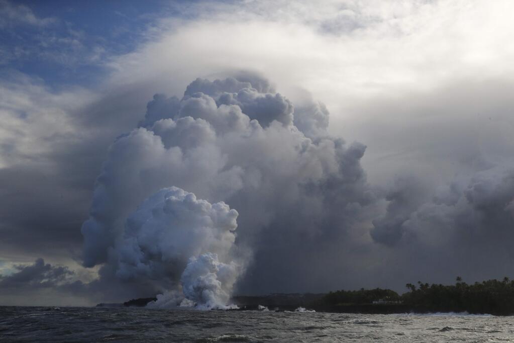 A plume of steam rises as lava enters the ocean near Pahoa, Hawaii, Sunday, May 20, 2018. Kilauea volcano that is oozing, spewing and exploding on Hawaii's Big Island has gotten more hazardous in recent days, with rivers of molten rock pouring into the ocean Sunday and flying lava causing the first major injury. (AP Photo/Jae C. Hong)