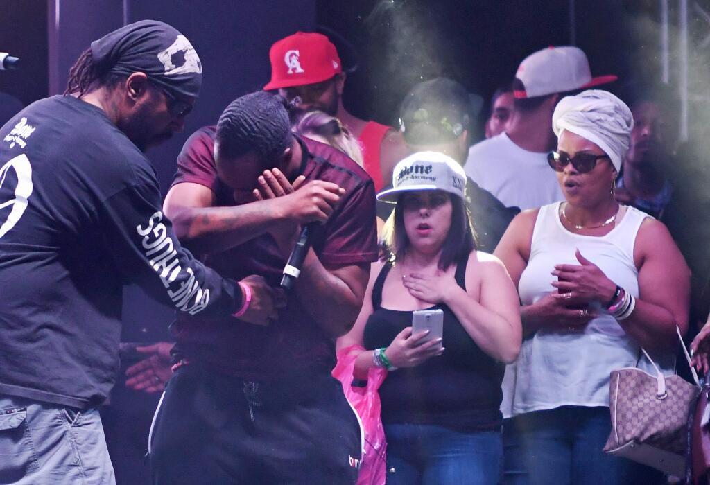 In this Sunday, Sept. 25, 2016, photo, Stanley Flesh-N-Bone Howse, of Bone Thugs-n-Harmony, center left, covers his face after he was hit with a drone onstage while performing during the High Life Music Festival in Victorville, Calif. (David Pardo/The Daily Press via AP)