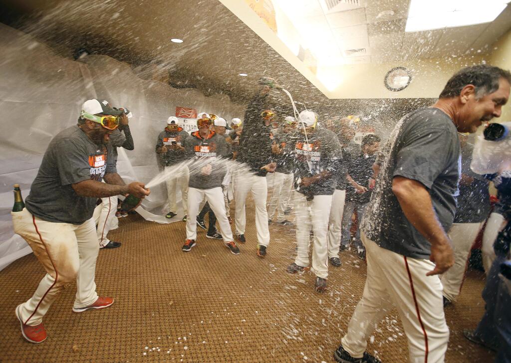 The Giants' Pablo Sandoval, left, celebrates with Bruce Bochy, right, in the locker room after the Giants' clinched the wildcard in the National League West in San Francisco, Thursday, Sept. 25, 2014. (AP Photo/Tony Avelar)