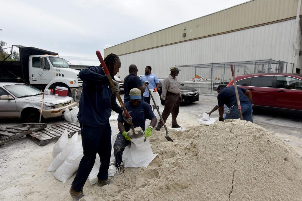 Employees from the City of Deerfield Beach Environmental Services fill sandbags for residents on Thursday, Oct. 6, 2016, in Deerfield Beach, Fal. The city gave out sandbags to residents of Deerfield Beach in preparation for Hurricane Matthew, which is forecasted to hit South Florida late Thursday or early Friday. (Maria Lorenzino/Sun Sentinel via AP)