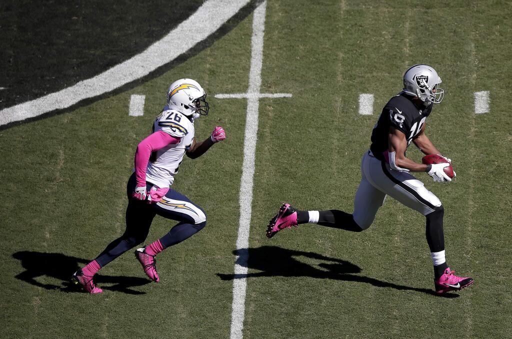 Oakland Raiders wide receiver Andre Holmes, right, runs past San Diego Chargers defensive back Brandon Flowers to score on a 77-yard touchdown pass during the first quarter of an NFL football game in Oakland Sunday, Oct. 12, 2014. (AP Photo/Marcio Jose Sanchez)