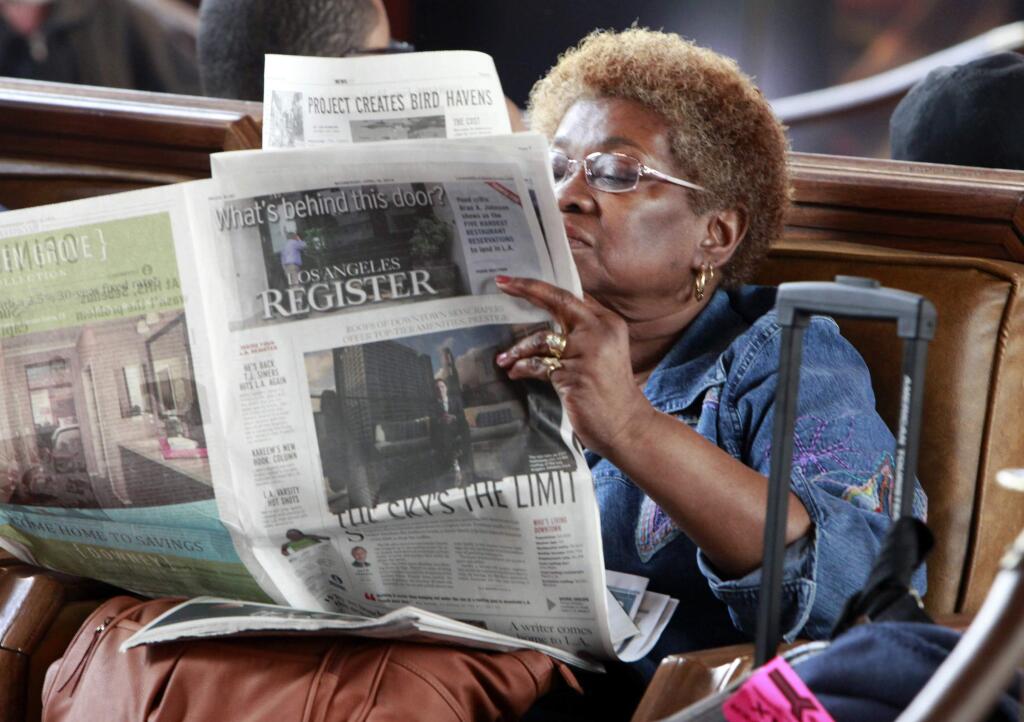 In this April 16, 2014 file photo, Dorothy Shumrt reads the Los Angeles Register newspaper on the day of its launch while waiting for a train at Union Station, in Los Angeles. The Los Angeles Register, which debuted in April as a challenger to the Los Angeles Times, has ceased publication. (AP Photo/Richard Vogel, File)