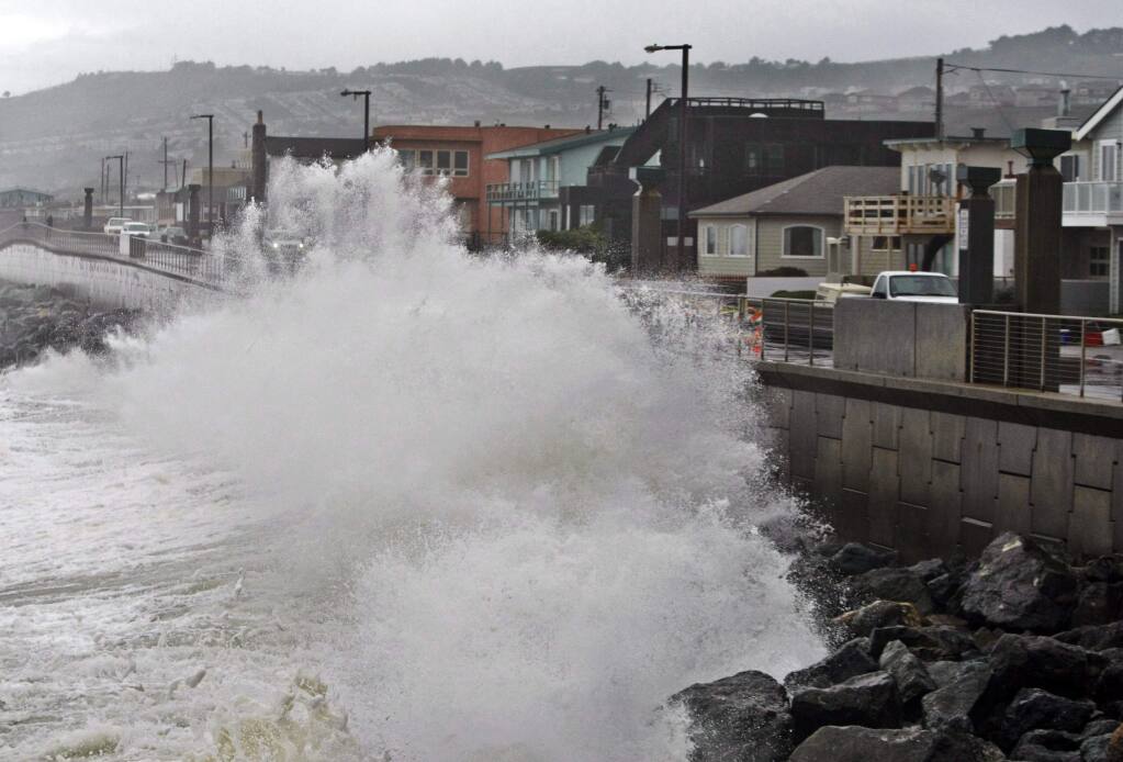 Waves pound a wall near buildings in Pacifica. (PAUL SAKUMA / Associated Press)