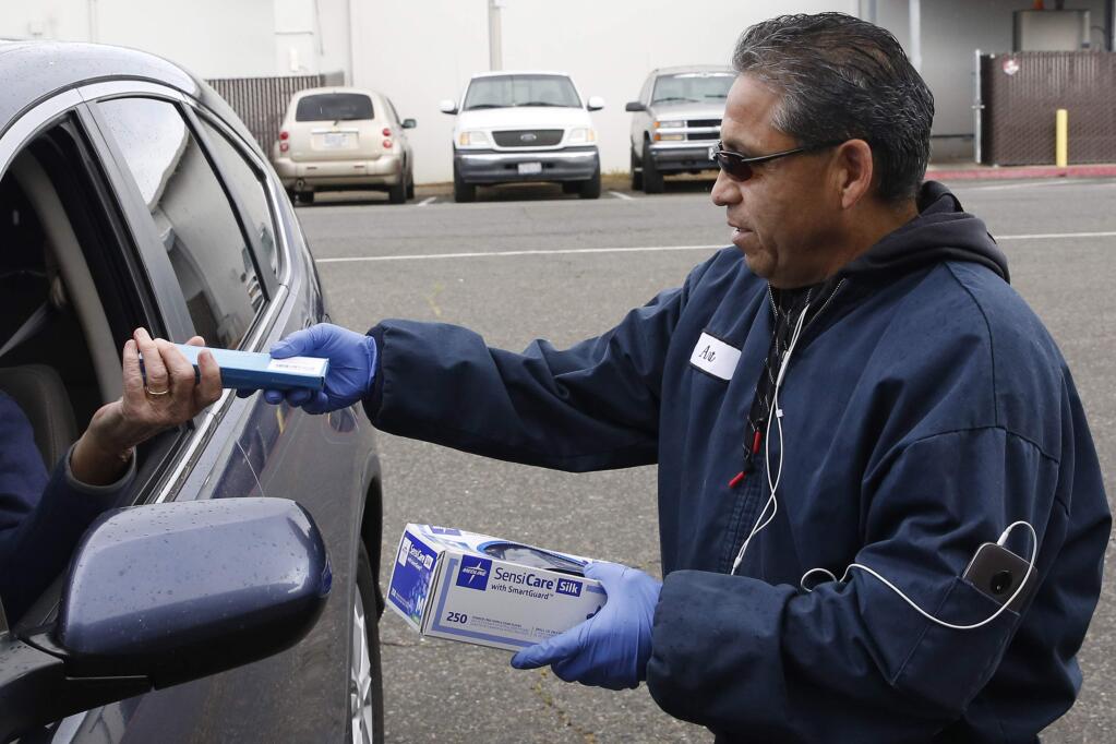 Volunteer Art Ponce is handed a box of sterile swabs and gloves from a donor, at a Sacramento County collection site in Sacramento, Calif., Thursday, March 26, 2020. Sacramento County is taking public donations of protective medical equipment, including N95 masks, surgical or procedural masks, non-latex gloves, hand sanitizers and disinfectant sprays among other items that will be distributed on a priority basis to area health professionals dealing with the coronavirus pandemic. (AP Photo/Rich Pedroncelli)