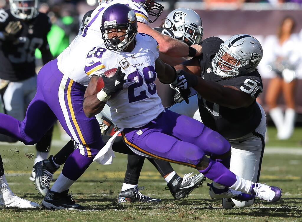 Oakland Raiders defensive tackle Dan Williams tackles Minnesota Vikings running back Adrian Peterson, during their game in Oakland on Sunday, November 15, 2015. The Vikings defeated the Raiders 30-14.(Christopher Chung/ The Press Democrat)