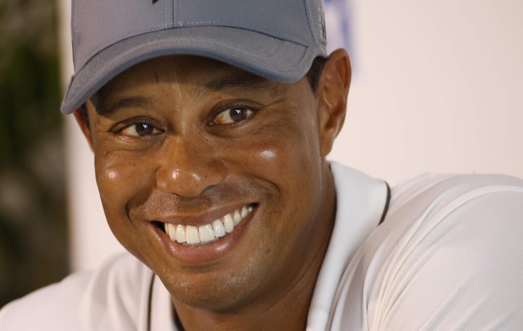 FILE - In this July 28, 2015, file photo, Tiger Woods smiles as he answers a question during a news conference prior to the start of the Quicken Loans National golf tournament, in Gainesville, Va. (AP Photo/Steve Helber, File)