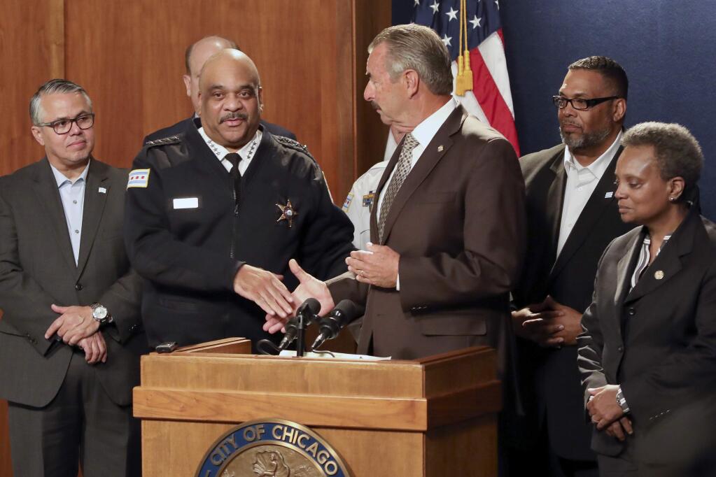 Former Los Angeles police Chief Charlie Beck, center, shakes hands with outgoing Superintendent Eddie Johnson, second from left, after he was named Chicago's interim police superintendent, Friday, Nov. 8, 2019 in Chicago. Chicago Mayor Lori Lightfoot, right, made the announcement a day after Johnson said he would retire after more than three years as the city's police chief and more than 30 years with the department. (AP Photo/Teresa Crawford)