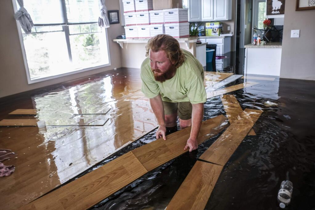 David Covington moves floating floor boards out of his path inside his flooded Conway, S.C. home on Sunday, Sept. 23, 2018. The Sherwood Drive area of Conway, S.C., began to look like a lake on Sunday as homes were submerged deeper than ever in flood waters that have already set historic records. (Jason Lee/The Sun News via AP)