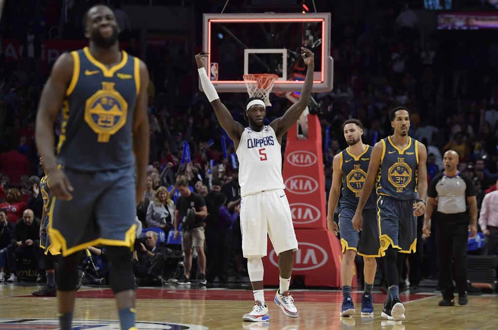 Los Angeles Clippers forward Montrezl Harrell, center, celebrates as time runs out in overtime as Golden State Warriors forward Draymond Green, left, guard Klay Thompson, second from right, and guard Shaun Livingston walk off the court in an NBA basketball game, Monday, Nov. 12, 2018, in Los Angeles. The Clippers won 121-116 in overtime. (AP Photo/Mark J. Terrill)