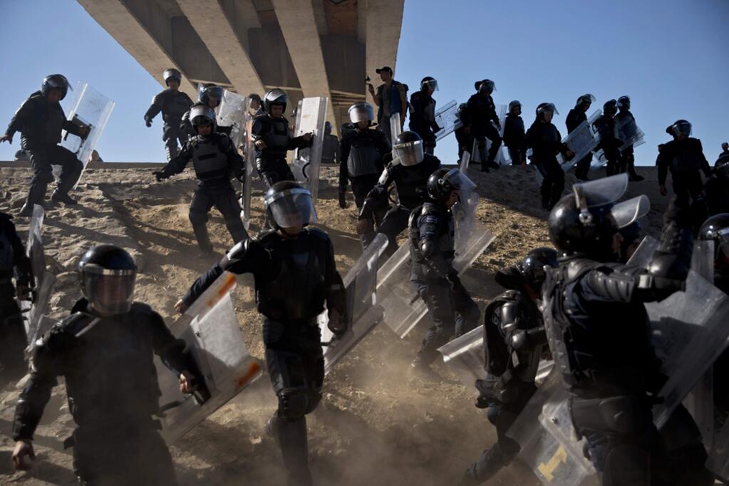 FILE - In this Nov. 25, 2018 file photo, Mexican police run as they try to keep migrants from getting past the Chaparral border crossing in Tijuana, Mexico, near San Ysidro, Calif. A San Diego TV station says the U.S. government ran an operation to screen journalists, activists and others while investigating last year's migrant caravan from Mexico. KNSD-TV says documents leaked by a Homeland Security source show a January database listing at least 10 journalists, seven of them U.S. citizens, as warranting secondary screening at U.S. points of entry. (AP Photo/Ramon Espinosa, File)