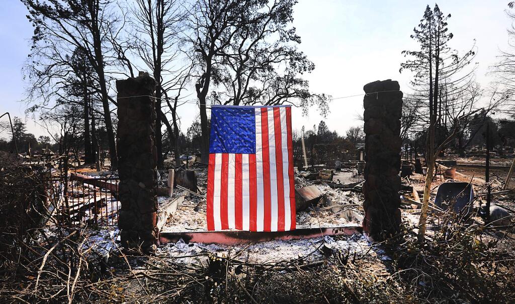 On Willowview Court in Santa Rosa, Calif., a homeowner displays an American flag amidst the destruction from a wildfire, Thursday Oct. 12, 2017. Since igniting Sunday in spots across eight counties, the fires have transformed many neighborhoods into wastelands. Thousands of homes and businesses have been destroyed and thousands of people were forced to flee. (Kent Porter/The Press Democrat via AP)