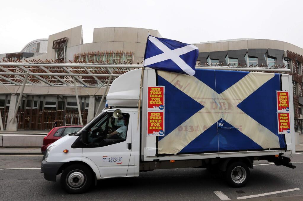 A Yes campaign van drives past the Scottish Parliament building in Edinburgh, Scotland, Wednesday, Sept. 17, 2014. The two sides in Scotland's independence debate are scrambling to convert undecided voters, with just one day to go until a referendum on separation. Anti-independence campaigners are pushing home their message that a 'No' vote doesn't mean the status quo. The three main British political parties are promising Scotland greater powers, including tax-raising authority, if it remains part of the United Kingdom. The Yes campaign says the promises are vague and reveal the No side's desperation, with polls suggesting the outcome will be close. Scottish Deputy First Minister Nicola Sturgeon said 'the only way to guarantee the real powers we need in Scotland is to vote Yes.' (AP Photo/Scott Heppell)
