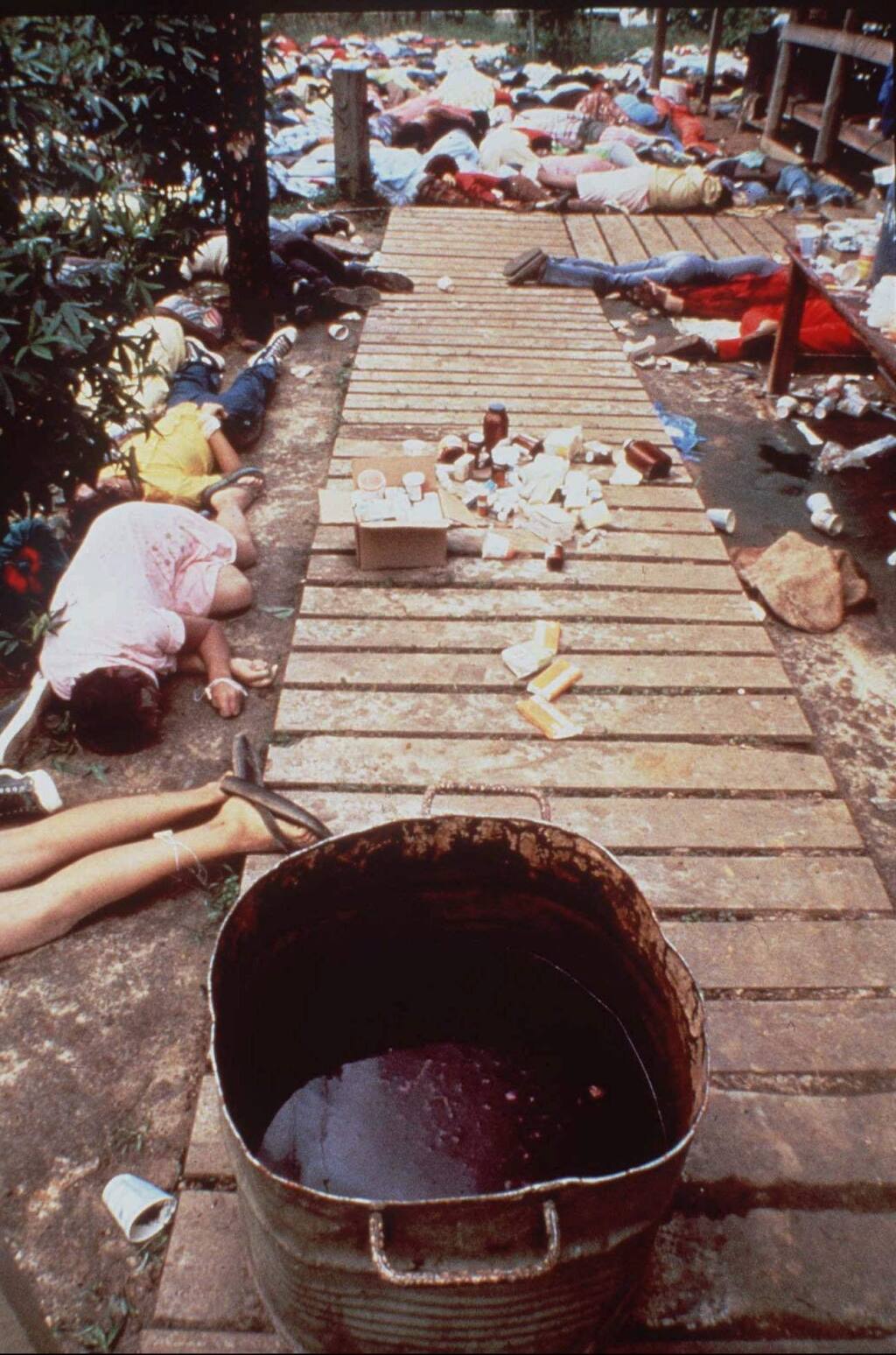 FILE - In this Nov. 20, 1978 file photo, a vat that contained a drink laced with deadly cyanide sits on a sidewalk at Peoples Temple in Jonestown, Guyana. The bodies of followers that drank the poison are strewn around the commune. Dozens of Peoples Temple members in Guyana survived the mass suicides and murders of more than 900 because they had slipped out of Jonestown or happened to be away Nov. 18, 1978. Those raised in the temple or who joined as teens lost the only life they knew. They have journeyed over the past 40 years through grief over lost loved ones, feeling like pariahs, building new lives and, finally, acknowledging that many had a role in enabling the Rev. Jim Jones to seize control over his followers. (AP Photo/Frank Johnston, Pool, File)