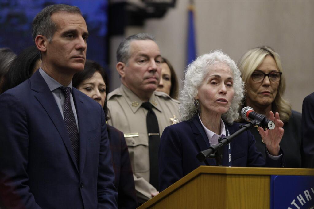 FILE - In this March 12, 2020 file photo Los Angeles County Public Health Director Barbara Ferrer, at podium, speaks at a news conference with Los Angeles Mayor Eric Garcetti, left, in Los Angeles. The U.S. Department of Justice on Friday, May 22, 2020, warned the mayor of Los Angeles and Ferrer, the county's top health officer that an extension of the coronavirus stay-at-home order may be unlawful. The vague letter sent to Garcetti and Ferrer did not spell out any specific violations, but noted concern about statements both had made publicly that restrictions may be prolonged without a vaccine. (AP Photo/Damian Dovarganes,File)