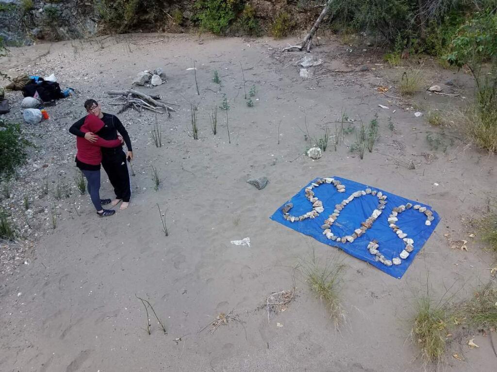 Krystal Ramirez and Hunter Whitson embrace after creating an SOS message out of rocks. (Curtis Whitson)