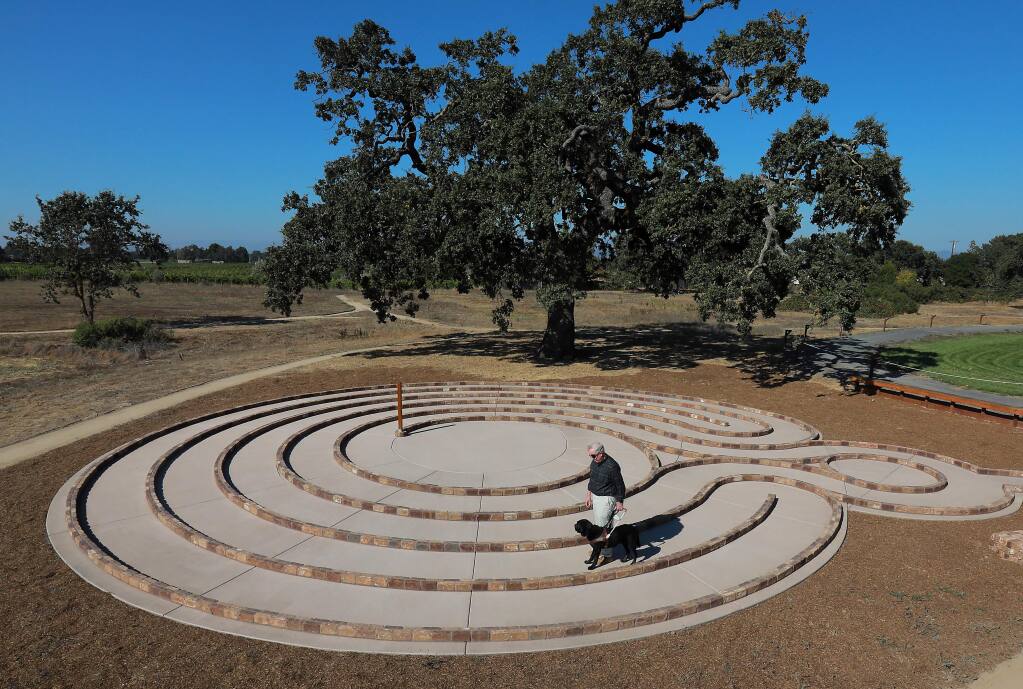 Bob Sonnenberg, who is legally blind, walks around the new labyrinth with his dog Langley at the Earle Baum Center for the Blind in Santa Rosa. (John Burgess/The Press Democrat)