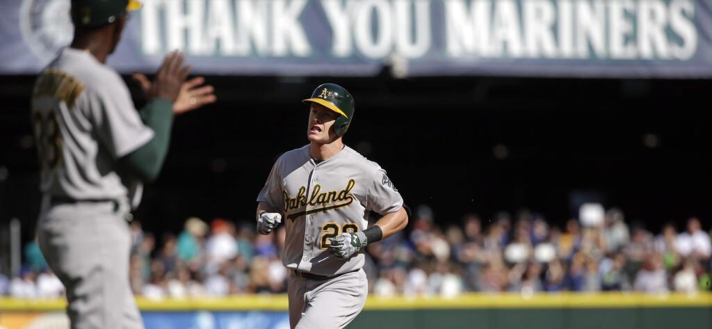 Oakland Athletics' Mark Canha, right, is applauded by third base coach Ron Washington as Canha rounds the bases on his home run against the Seattle Mariners in the third inning of a baseball game, Sunday, Oct. 4, 2015, in Seattle. (AP Photo/Elaine Thompson)