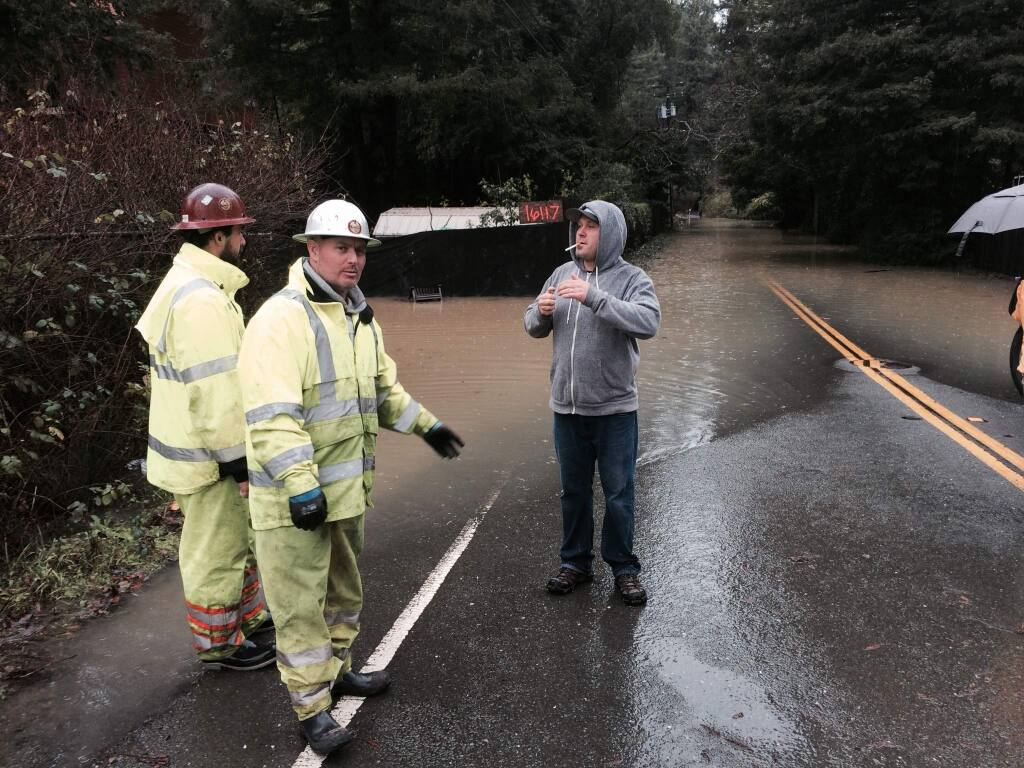 A contractor tries to convince Sonoma County roads crews to close Neely Road for fear wakes will topple a nearby home on Friday, Dec. 12, 2014. (JOHN BURGESS/ PD)