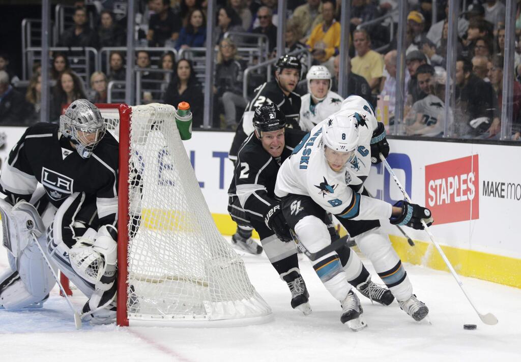 San Jose Sharks' Joe Pavelski, right, moves the puck under pressure by Los Angeles Kings' Matt Greene as the Kings goalie Jonathan Quick, left, watches during the first period of an NHL hockey game, Wednesday, Oct. 7, 2015, in Los Angeles. (AP Photo/Jae C. Hong)