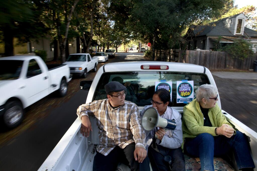(From left) Karym Sanchez, Luis Santoyo, and Ann Boone ride in the back of a pick-up truck through the Roseland area and try to reach out to voters with a megaphone as part of the North Bay Organizing Project's voter engagement campaign, 'Make Your Neighborhood Count' in Santa Rosa, California on Tuesday, November 4, 2014. (BETH SCHLANKER/ The Press Democrat)