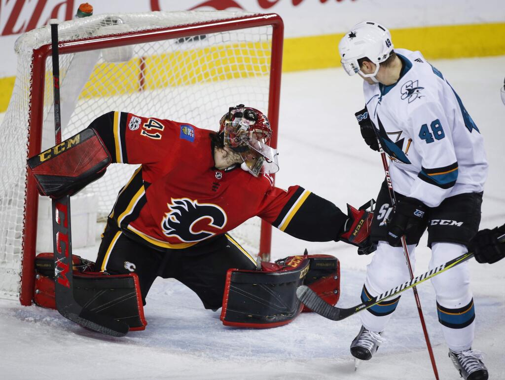 The San Jose Sharks' Tomas Hertl, right, looks back as Calgary Flames goalie Mike Smith grabs the puck during a game in Calgary, Thursday, Dec. 14, 2017. (Jeff McIntosh/The Canadian Press via AP)
