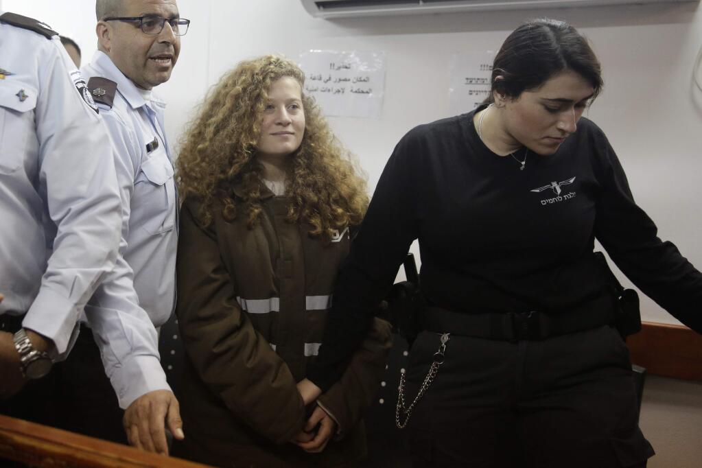 FILE - In this Jan. 15, 2018 file photo, Ahed Tamimi is brought to a courtroom inside the Ofer military prison near Jerusalem. Tamimi is to go on trial Tuesday, Feb. 13, 2018, before an Israeli military court, for slapping and punching two Israeli soldiers in December. Palestinians say her actions embody their David vs. Goliath struggle against a brutal military occupation, while Israel portrays them as a staged provocation meant to embarrass its military. Tamimi is one of an estimated 350 Palestinian minors in Israeli jails. (AP Photo/Mahmoud Illean, File)