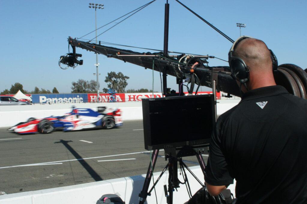 A cameraman from IMS Productions wields a jib camera at Sonoma Raceway to follow the action of the IndyCar races. Almost 20 cameras cover the action from the track, and many of the cars have two or three cameras on board as well. (Christian Kallen/Index-Tribune)
