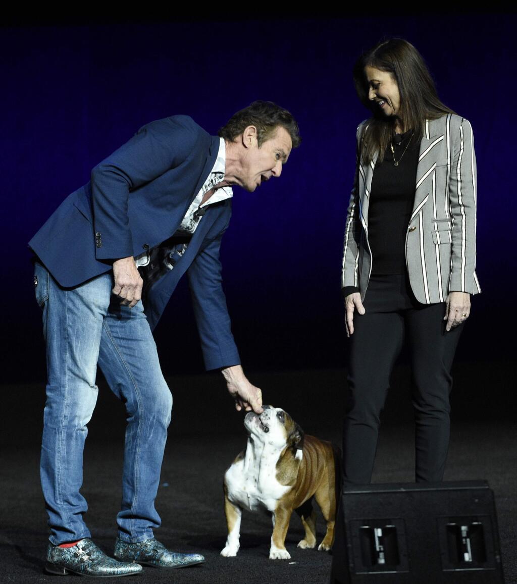 FILE - In this April 3, 2019, file photo, Dennis Quaid, left, a cast member in the upcoming film 'A Dog's Journey,' attends to his dog as the film's director Gail Mancuso looks on during the Universal Pictures presentation at CinemaCon 2019, the official convention of the National Association of Theatre Owners (NATO) at Caesars Palace in Las Vegas. The 2018 family hit “A Dog's Purpose” was marred by accusations of animal abuse after a video of a frightened dog that appeared to be forced into rushing water during the making of the film was posted by TMZ. Quaid starred in both movies (Photo by Chris Pizzello/Invision/AP, File)