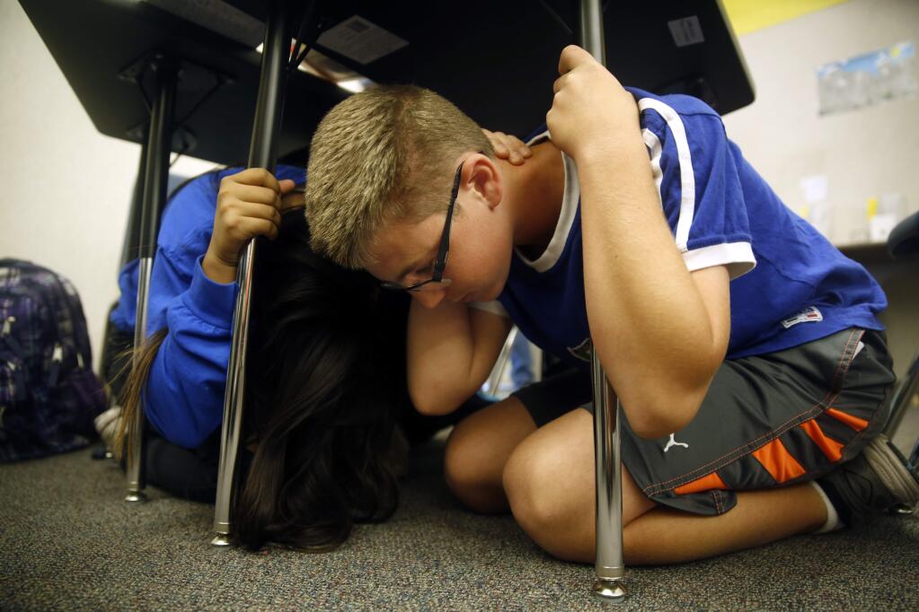 Seventh grader Blake Grudzien, 12, huddles under his desk in Gloria Hurtado's math class, as the class practices earthquake safety during 'The Great California ShakeOut' drill at Santa Rosa Middle School in Santa Rosa, on Thursday, October 20, 2016. (BETH SCHLANKER/ The Press Democrat)