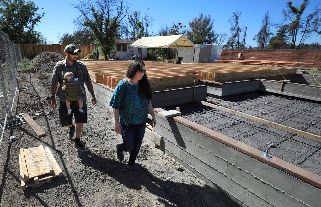 Alex and Heather Apons take their four month-old son Etienne on a tour around their home which is being rebuilt nine months after the Tubbs fire razed the home in Coffey Park, Monday, July 16, 2018 in Santa Rosa. (Kent Porter / The Press Democrat) 2018