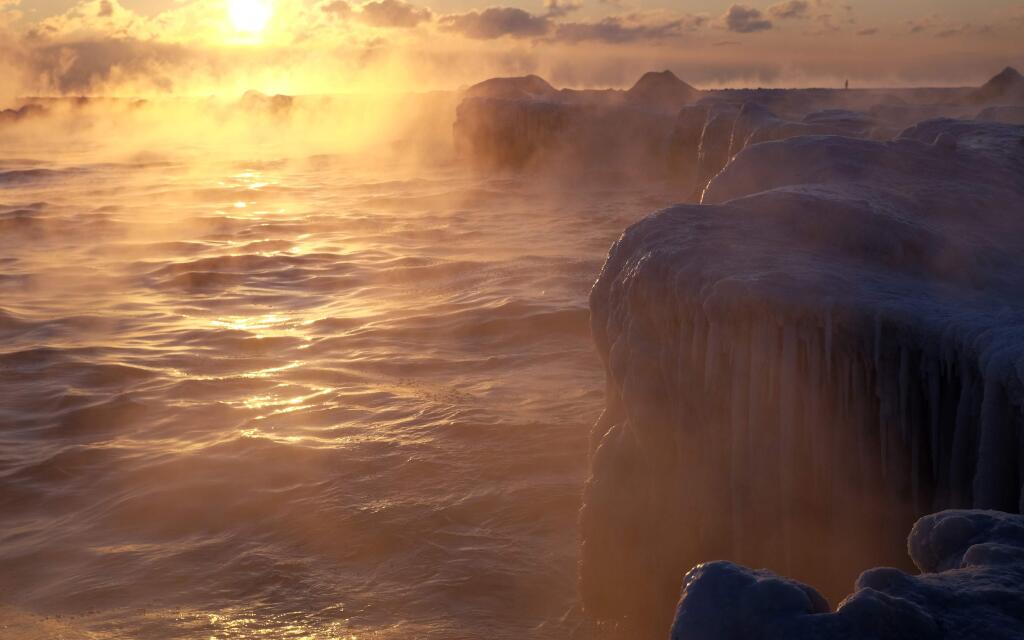 The sun rises on Lake Michigan as ice forms along the shore, Thursday, Feb. 19, 2015, in Chicago. Temperatures have dipped to as low as -13 in parts of Illinois with wind chills forecast to fall to between 20 and 30 degrees below zero. (AP Photo/Kiichiro Sato)