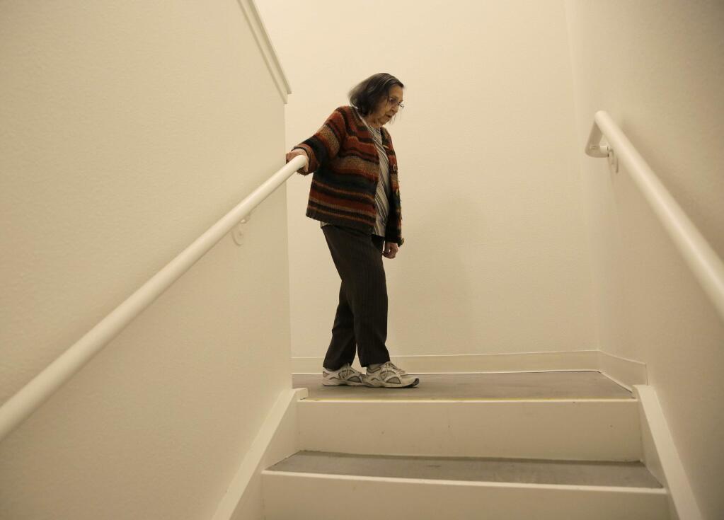 Helen Wagar, who is in her 80s, walks over the spot in a stairway where she fell over another woman who was laying in the dark during the recent power blackouts at the Villas at Hamilton housing complex for low income seniors Wednesday, Oct. 30, 2019, in Novato, Calif. Pacific Gas & Electric officials said they understood the hardships caused by the blackouts but insisted they were necessary. (AP Photo/Eric Risberg)