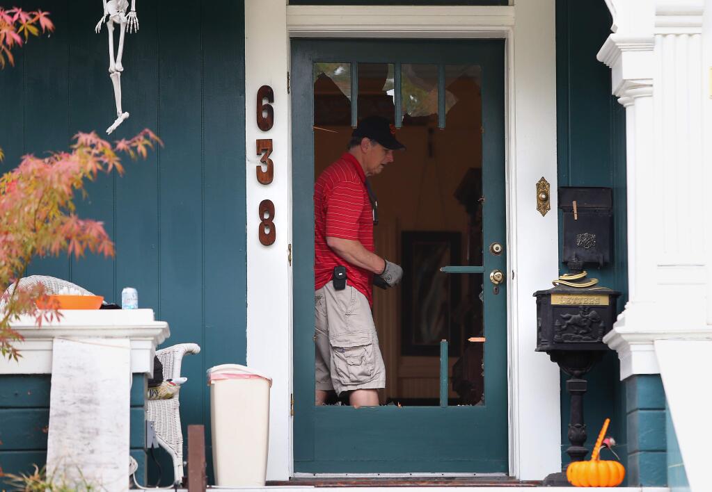 An unidentified man walks past the broken front door of the Wright Street home in Santa Rosa where a homicide occurred on Sunday, Oct. 19, 2014. Photo taken Monday, Oct. 20, 2014. (CHRISTOPHER CHUNG/ PD FILE)