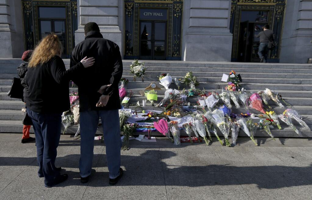 A woman and man pause to look at a memorial for Mayor Ed Lee on the steps of City Hall in San Francisco, Wednesday, Dec. 13, 2017. Lee died Tuesday at 65 after collapsing while grocery shopping. (AP Photo/Jeff Chiu)