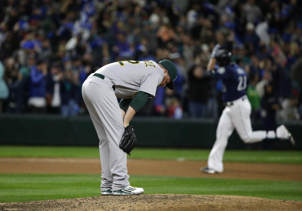 Oakland Athletics pitcher Sean Doolittle, left, reacts on the mound as Seattle Mariners' Nelson Cruz rounds the bases after hitting a two-run home run during the seventh inning of a baseball game, Saturday, Oct. 1, 2016, in Seattle. (AP Photo/Ted S. Warren)