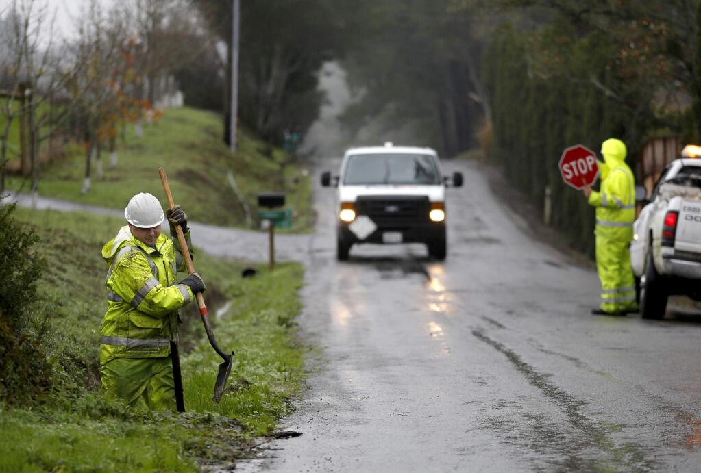 In preparation for heavy rains, Alex Miller, a maintenance worker with Sonoma County, digs out the end of a culvert along Burnside Rd. on Monday, December 8, 2014 in Sebastopol, California . (BETH SCHLANKER/ The Press Democrat)